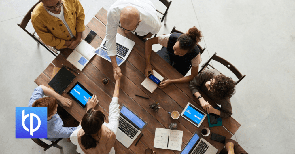 eight people working on laptops phones notepads at a table
