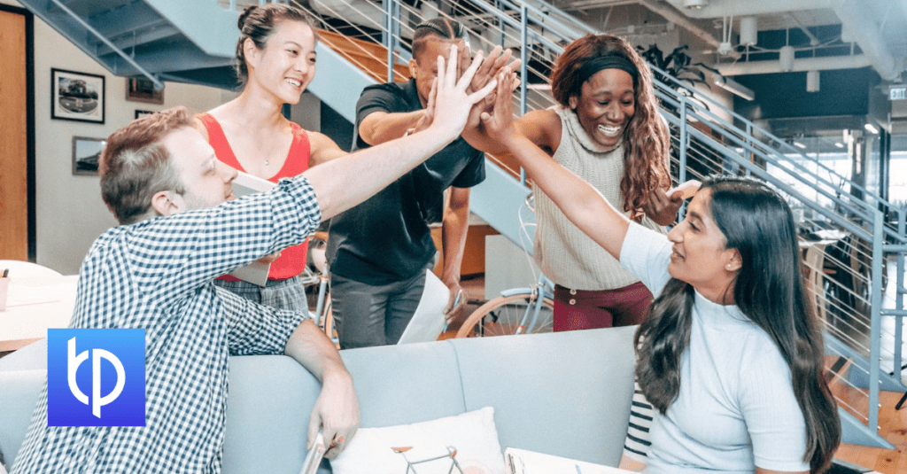 five people high fiving in a modern office foyer