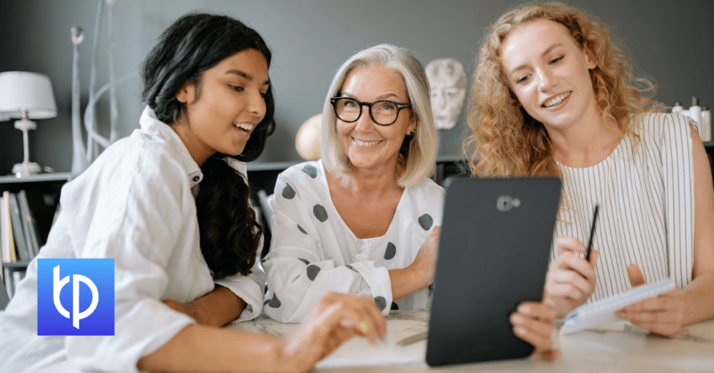 Two young women and one older woman with a tablet